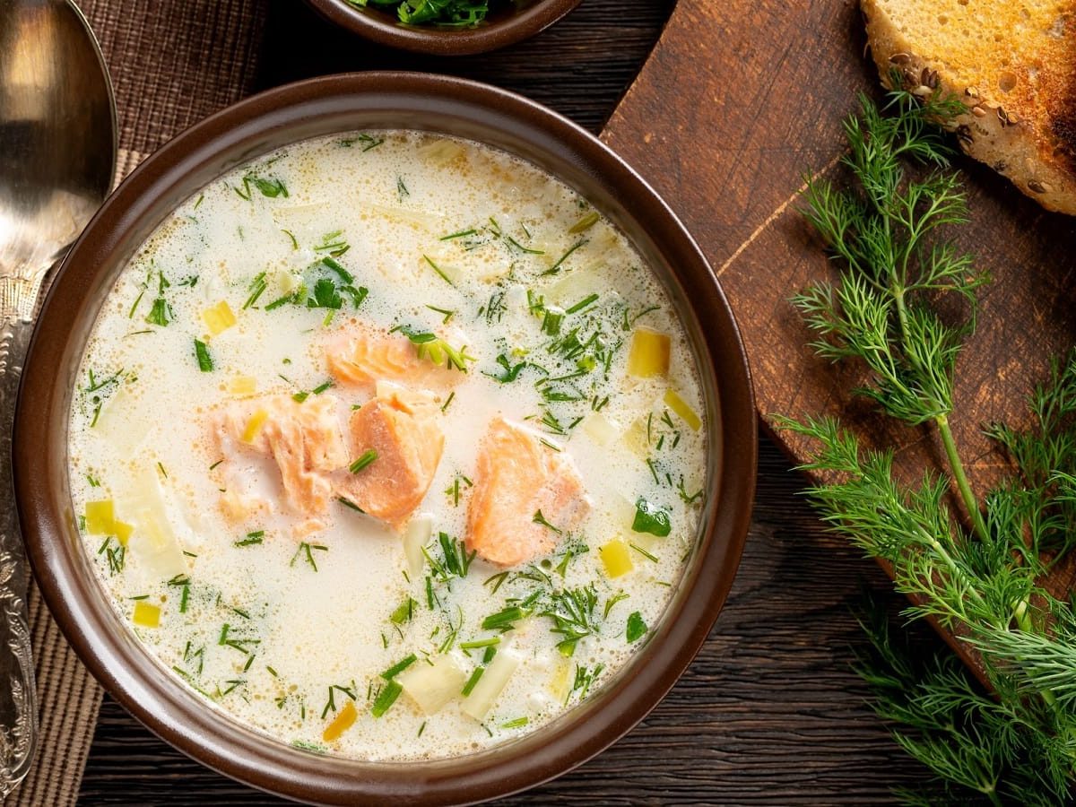 Eine runde Schüssel mit Lachs-Lauchcremesuppe mit Dill.