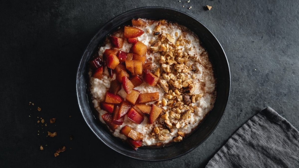 Eine schwarze Schüssel mit Pflaumen-Porridge mit Walnüssen.