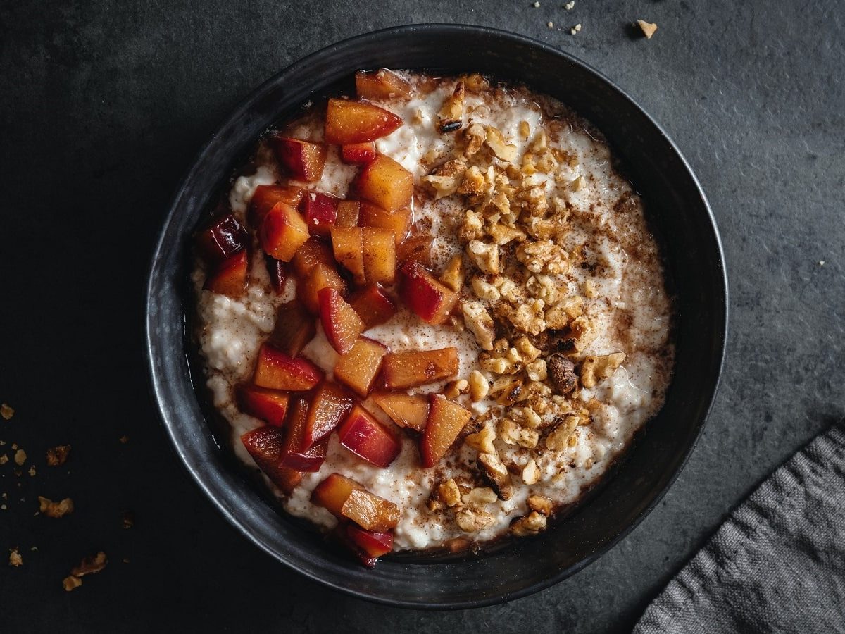 Eine schwarze Schüssel mit Pflaumen-Porridge mit Walnüssen.