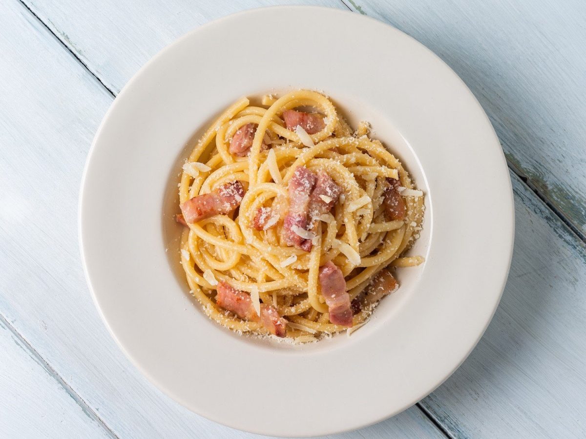 Pasta alla gricia mit Speck und Käse auf weißem Teller.