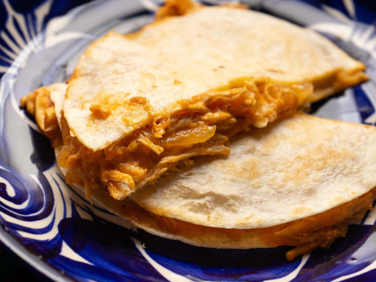 Quesadilla Tinga de Pollo auf blau-weißem Teller angerichtet. Draufsicht.