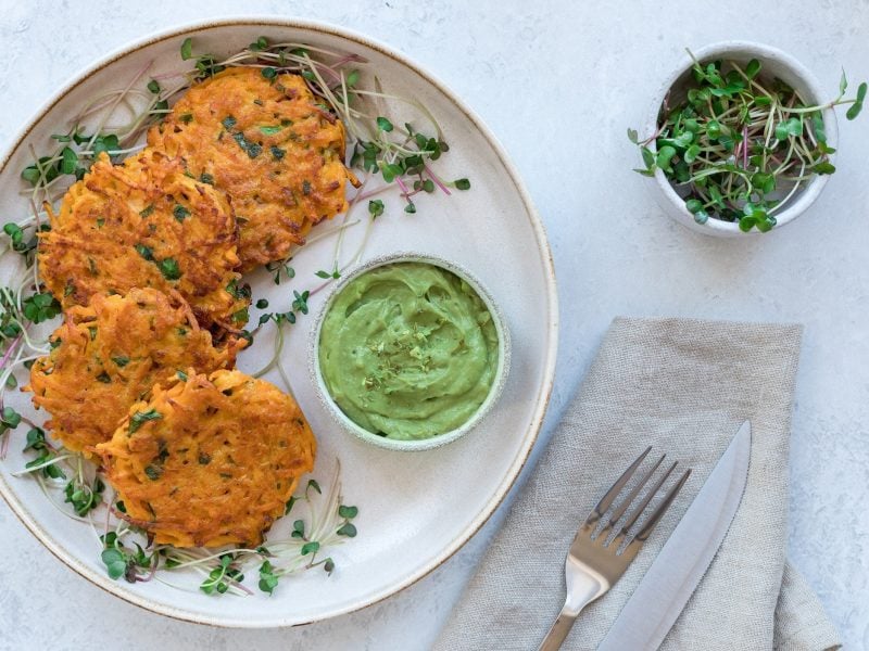 Ein Teller Kürbis-Frikadellen mit einer Schale Guacamole und Kresse, alles Draufsicht.