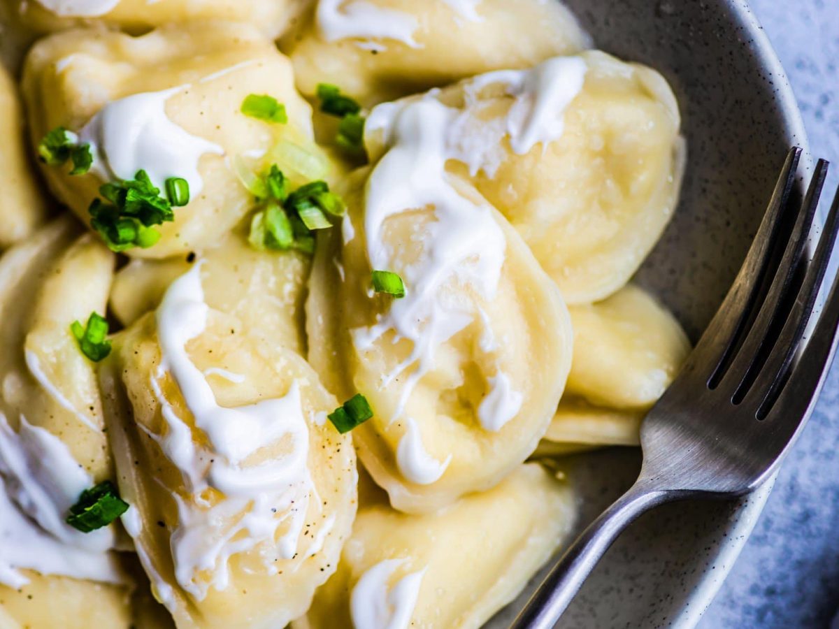 Maultaschen mit Schmandsauce auf grauem Teller.