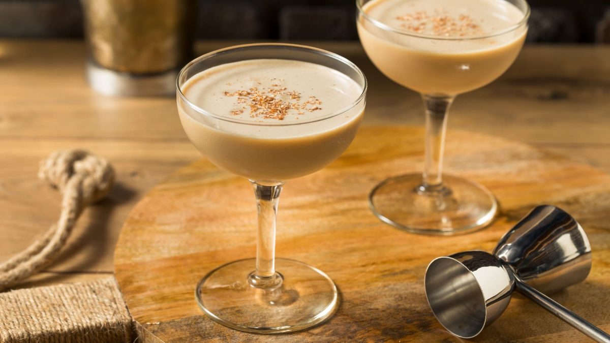 Ein Holztisch mit zwei Gläsern, gefüllt mit dem Cocktail Brandy Alexander.