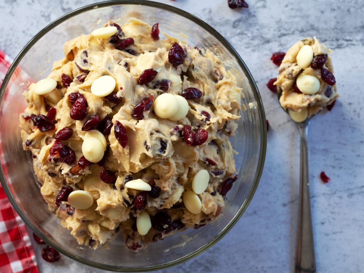 Cookie Dough mit Cranberries und weißer Schokolade in einer Schüssel, daneben ein Löffel in der Draufsicht.