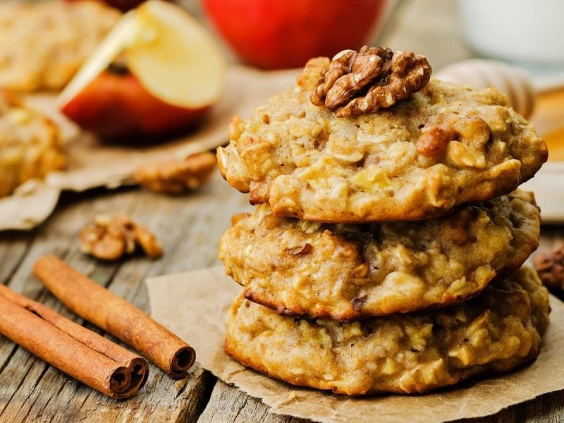 Drei Apfel-Haferflocken-Kekse auf einem Holztisch.