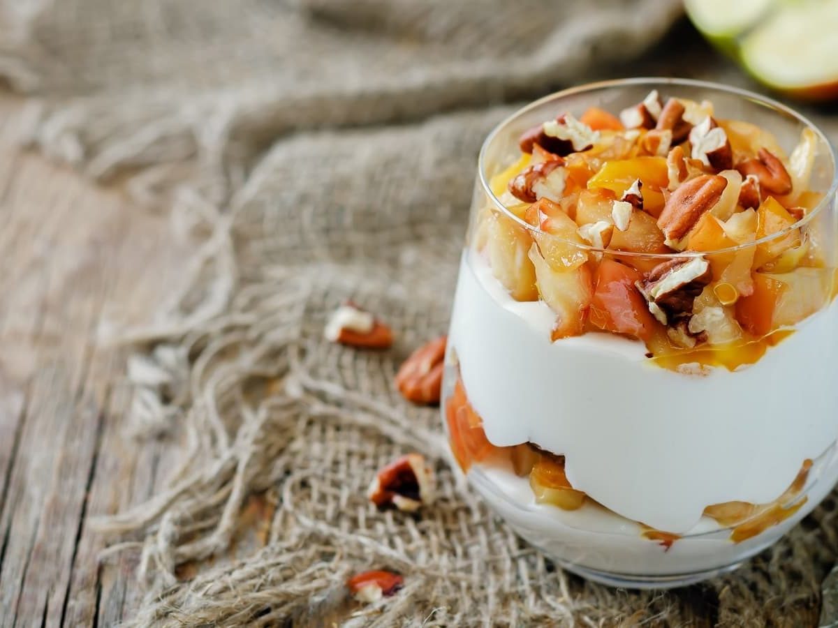 Ein kleines Gläschen mit Apfel-Joghurt-Creme auf einem Stofftuch.