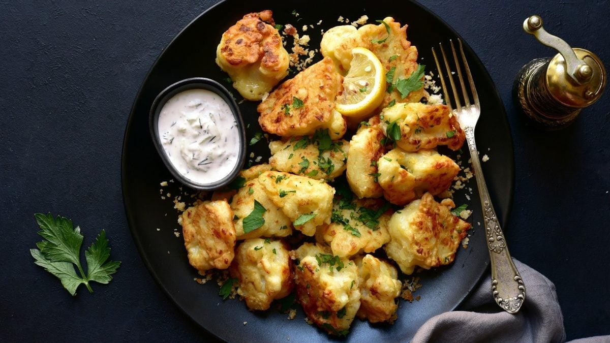 Ein schwarzer Teller mit Blumenkohl-Nuggets mit Käse.