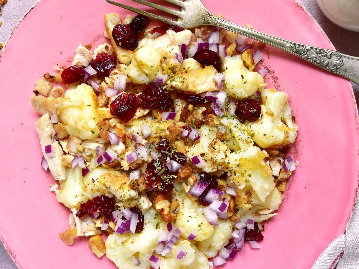 Ein rosa Teller mit Blumenkohl-Salat mit Cranberries.