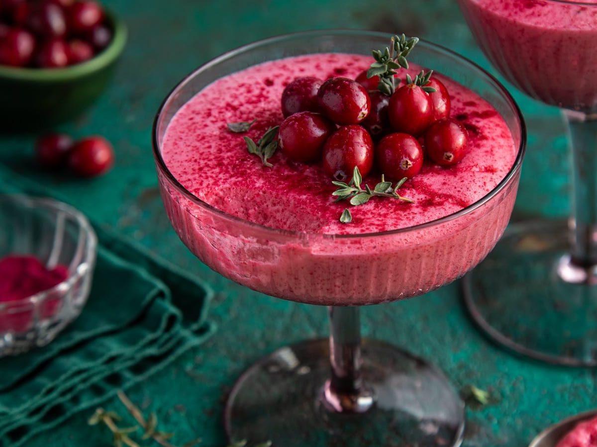 Ein Glas mit Cranberry-Mousse auf einem grünen Tisch.