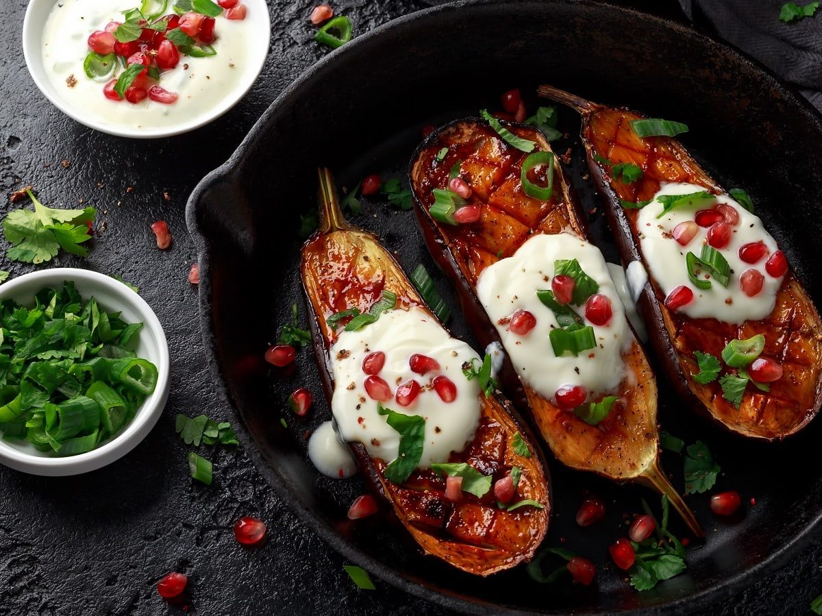 Eine schwarze Pfanne mit gegrillter Aubergine mit Joghurtsauce