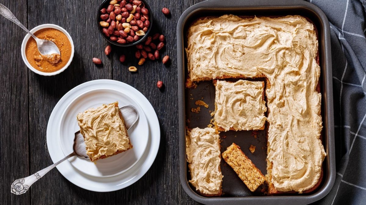 Ein Blech mit Peanut Butter Sheet Cake auf einem dunklen Tisch.