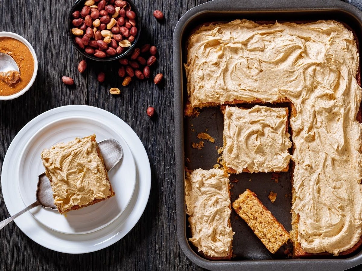 Ein Blech mit Peanut Butter Sheet Cake auf einem dunklen Tisch.