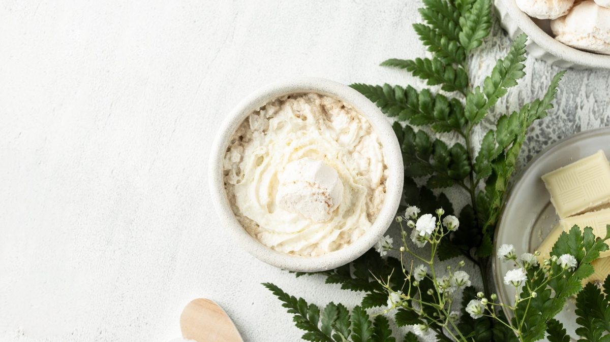 Ein Glas mit Vanillekipferl-Creme neben einem Tannenzweig.