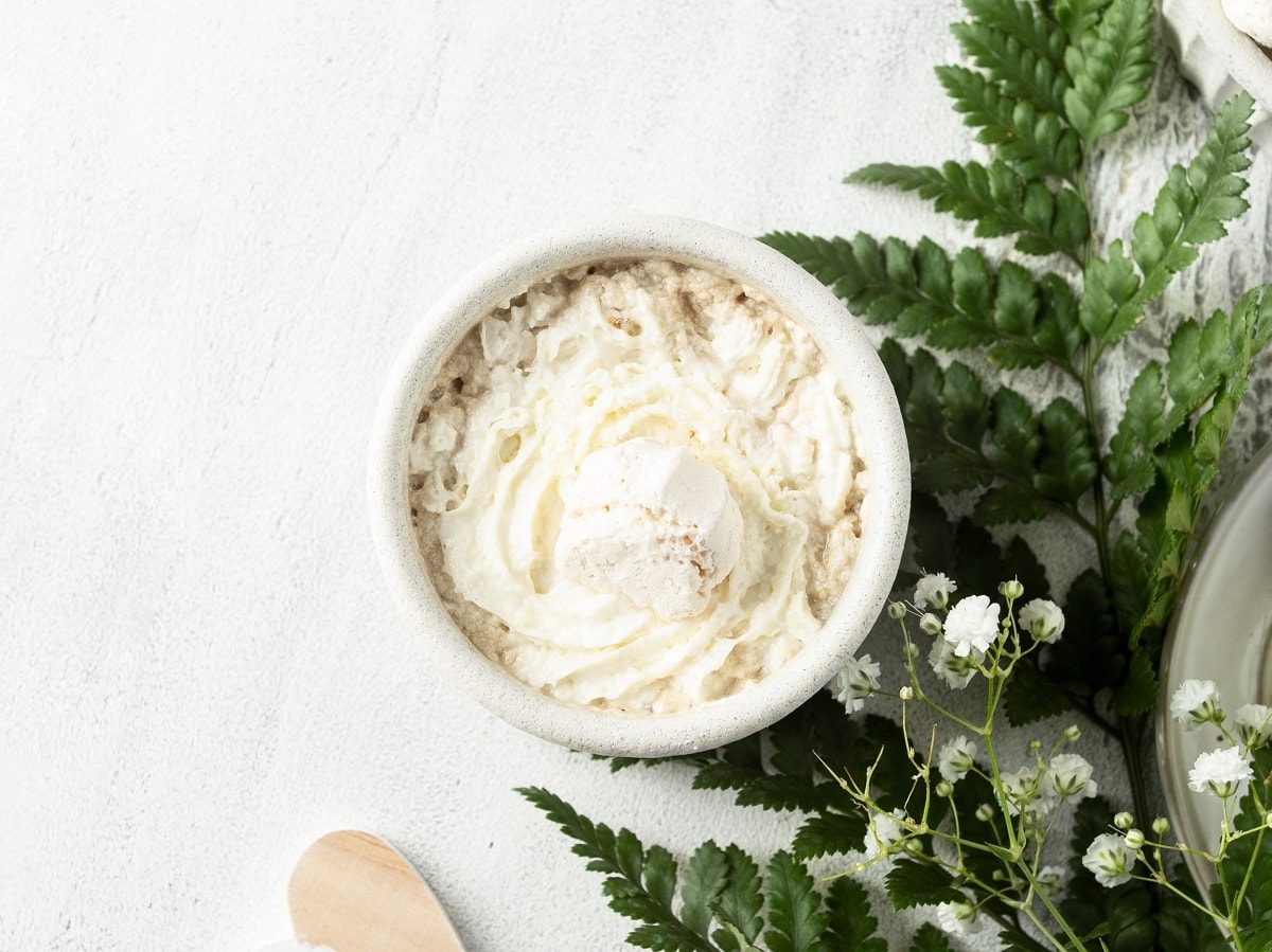 Ein Glas mit Vanillekipferl-Creme neben einem Tannenzweig.