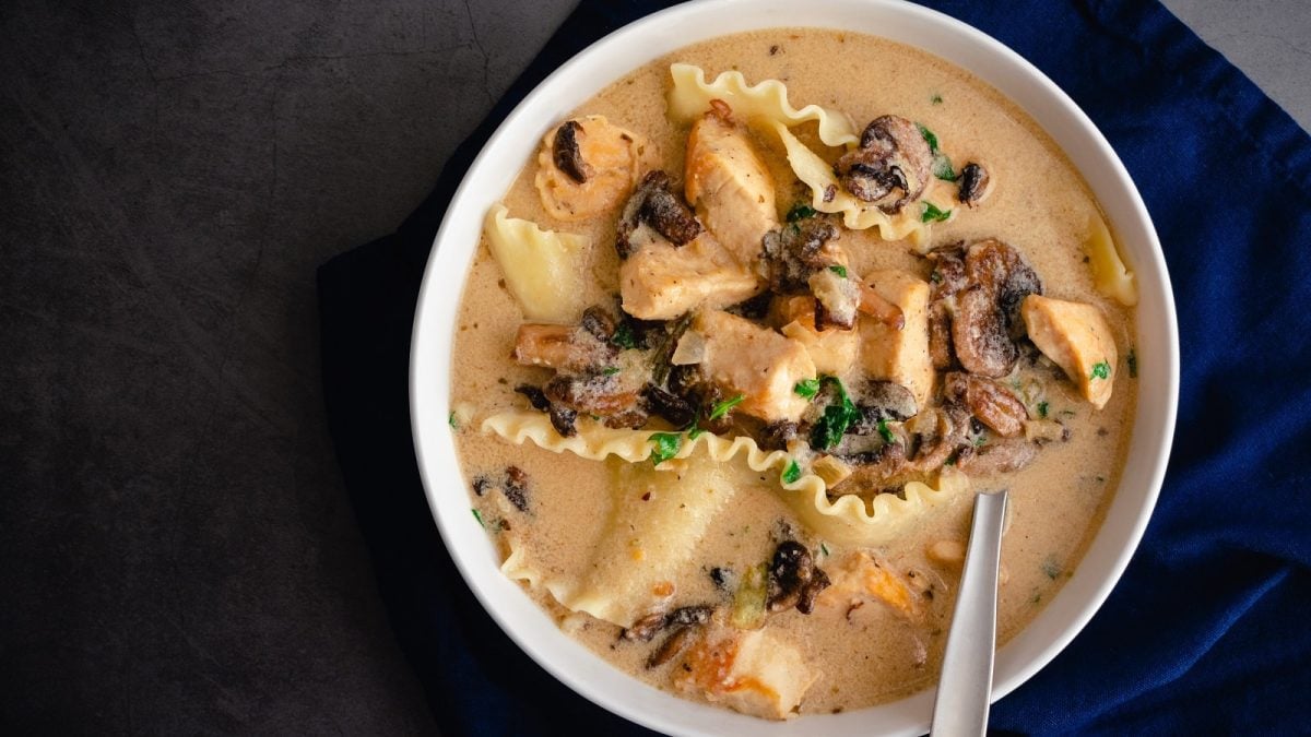 Eine Schüssel mit weißer Lasagne Suppe auf dunklem Hintergrund.