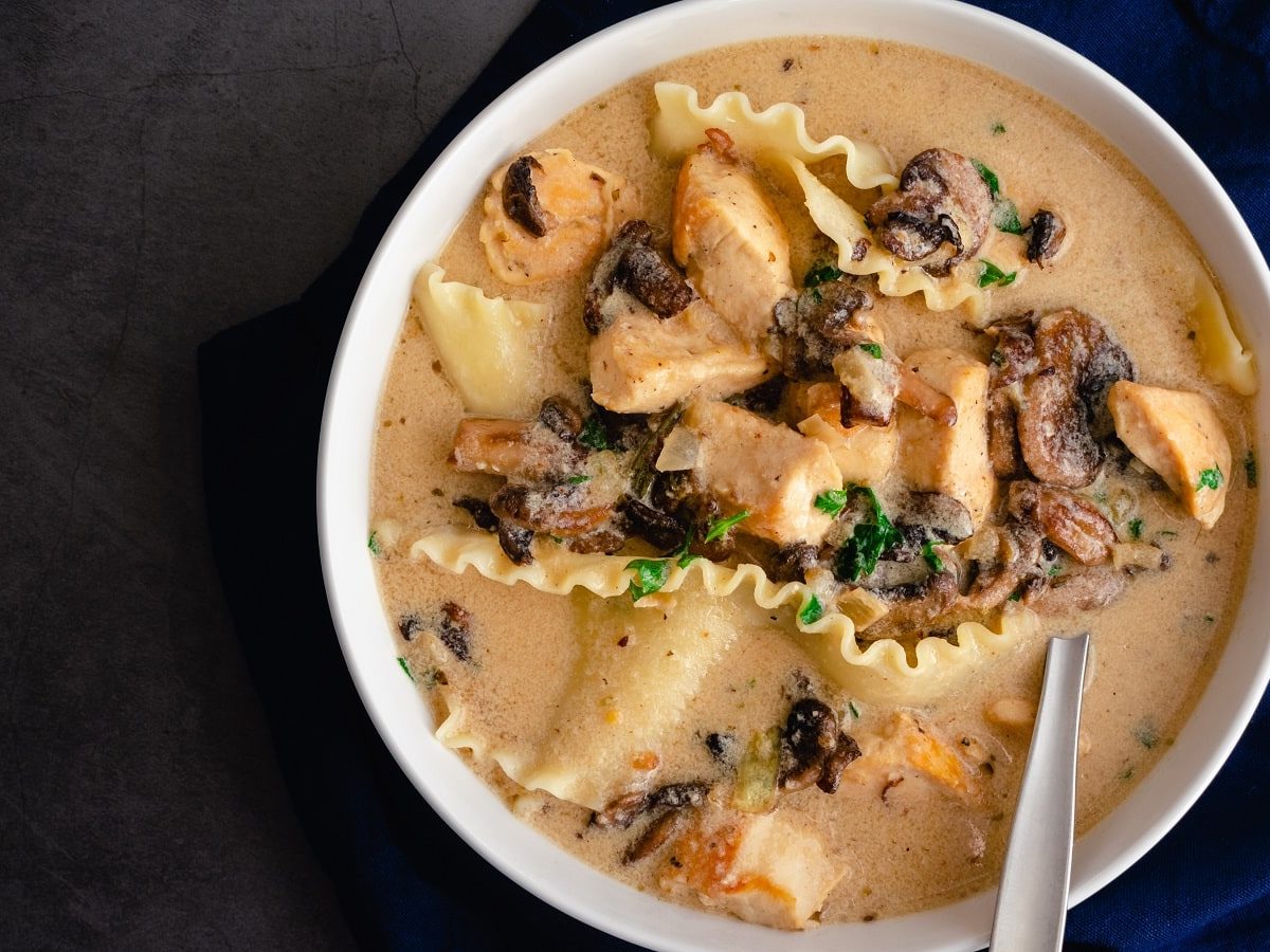 Eine Schüssel mit weißer Lasagne Suppe auf dunklem Hintergrund.