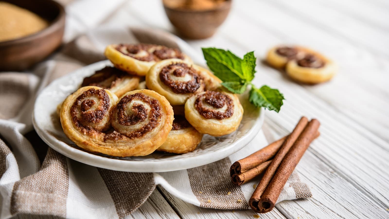 Ein Teller mit Zimt-Palmiers auf einem weißen Holztisch.