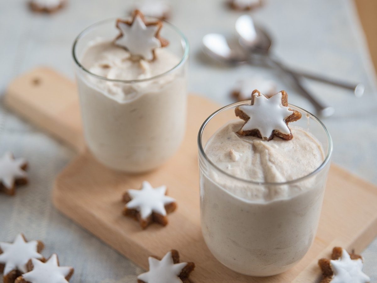 Zwei Gläser mit Zimtstern-Creme auf einem Holztablett.