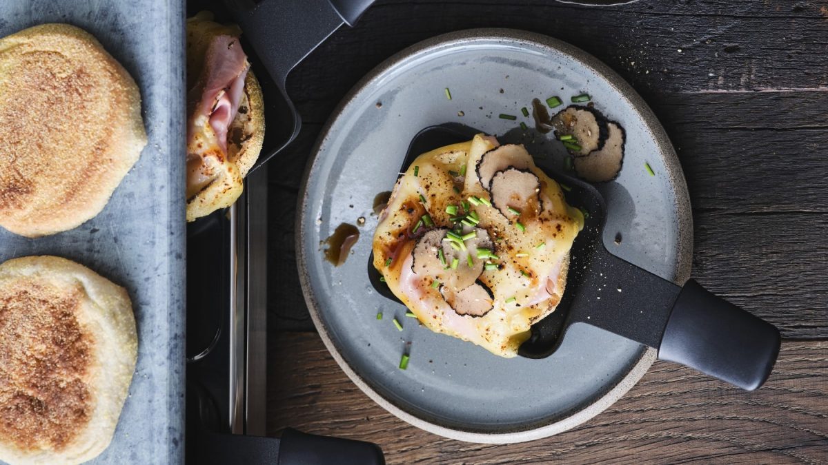 Karlsbader Schnitte, mit Käse überbackenes Schinkentoast mit Trüffel und Worcestersauce auf einem Raclette-Pfännchen serviert.