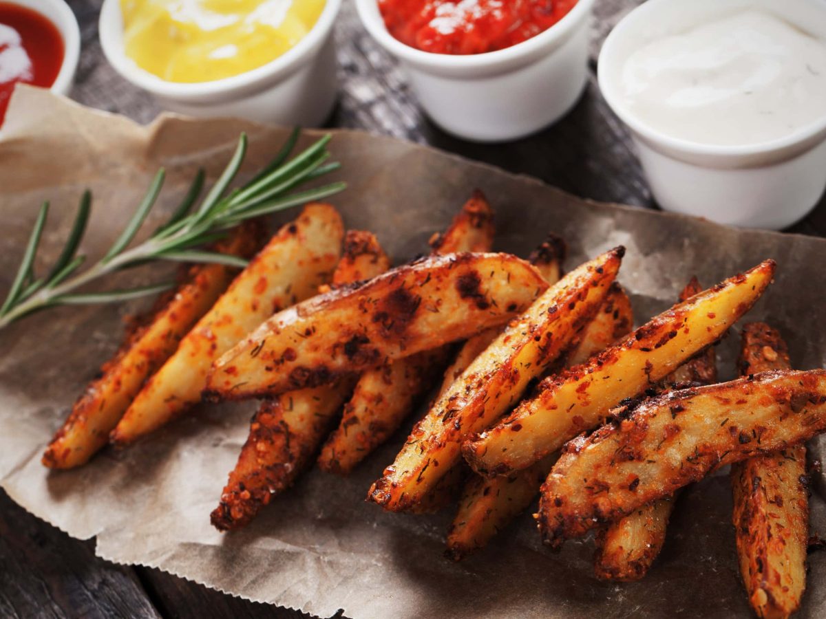 Roasted Garlic Wedges Hot and Spicy mit Dips auf Backpapier. Draufsicht