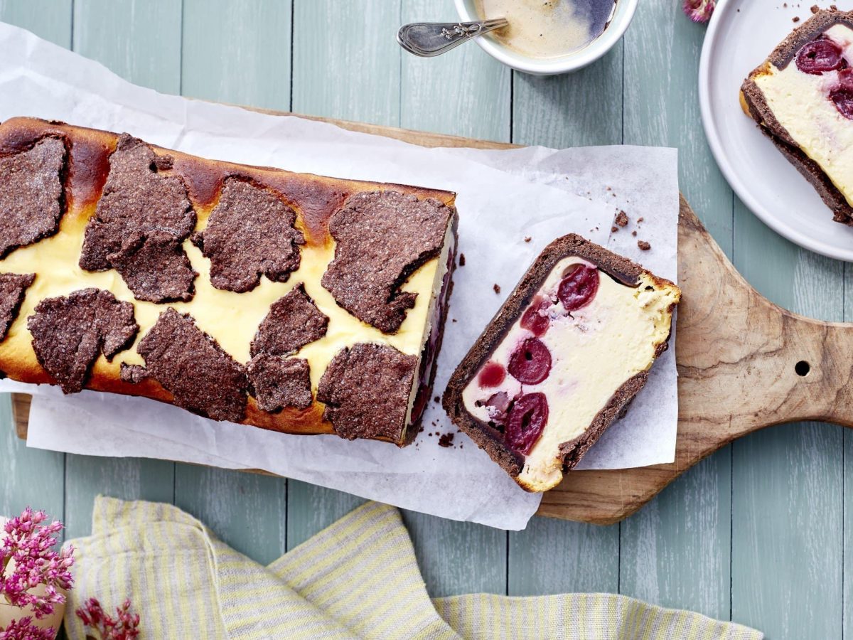 Schwarzwälder Zupfkuchen auf einem Holzbrett in der Draufsicht, daneben ein Teller mit einem Stück davon.