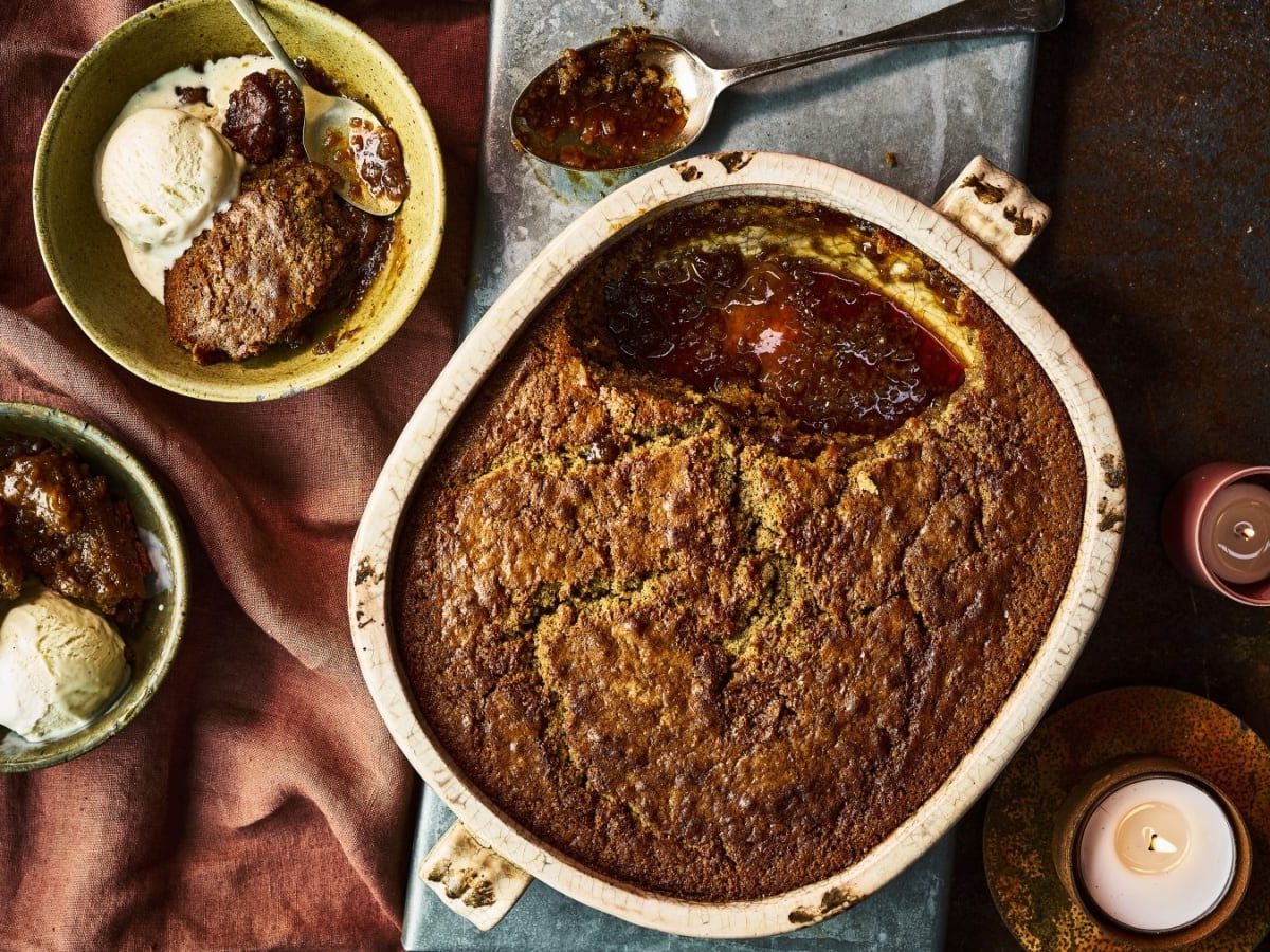 Draufsicht: Auflaufform mit self-saucing sticky Lebkuchen-Pudding. Zwei Teller angerichtet mit Pudding und Vanilleeis