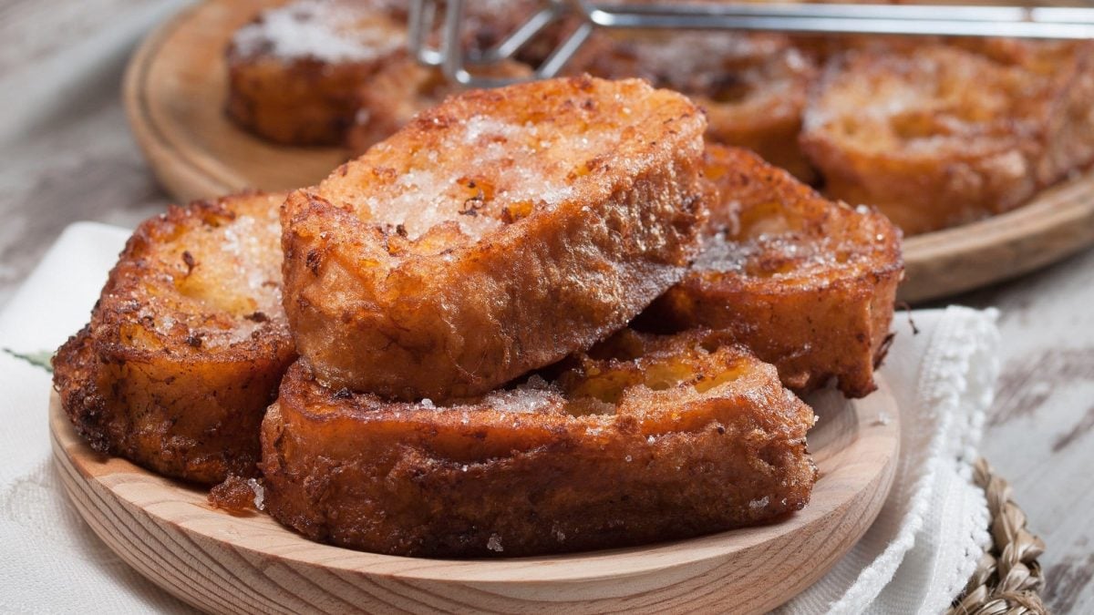 Ein Holzteller Stollen-French-Toasts mit Zucker bestreut.