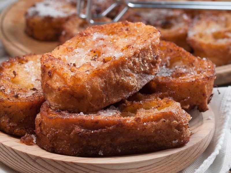 Ein Holzteller Stollen-French-Toasts mit Zucker bestreut.