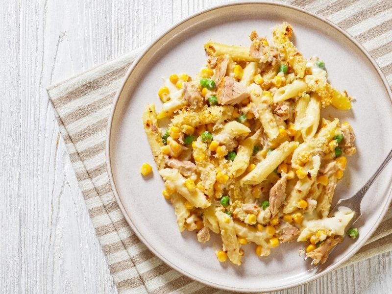 Ein weißer Teller auf einem hellen Holz-Untergrund mit der Thunfisch-Pasta.