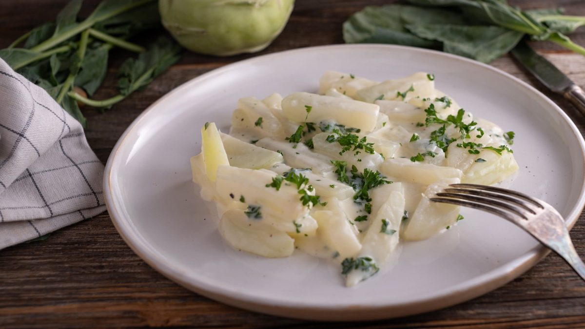 Ein Teller veganer Rahmkohlrabi mit Petersilie bestreut.