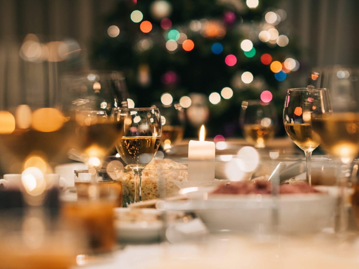 Vorspeisen zum Weihnachtsdinner gedeckter Tisch mit gefüllten Gläsern.Im Hintergrund Weihnachtsbaum. Frontalaufnahme.