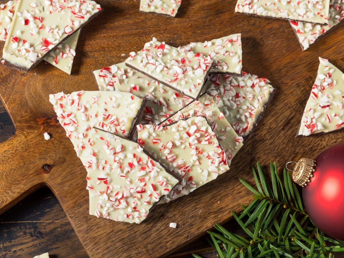 Die weihnachtliche Bruchschokolade auf einem dunklen Holzbrett mit weihnachtlicher Dekoration.