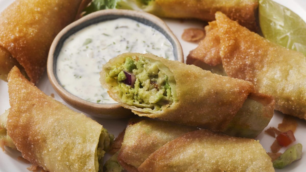 Eine Portion mit Avocado-Frühlingsrollen neben einem Dip.