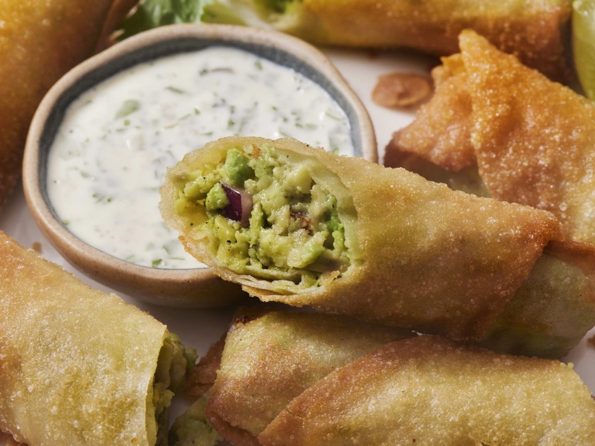 Eine Portion mit Avocado-Frühlingsrollen neben einem Dip.