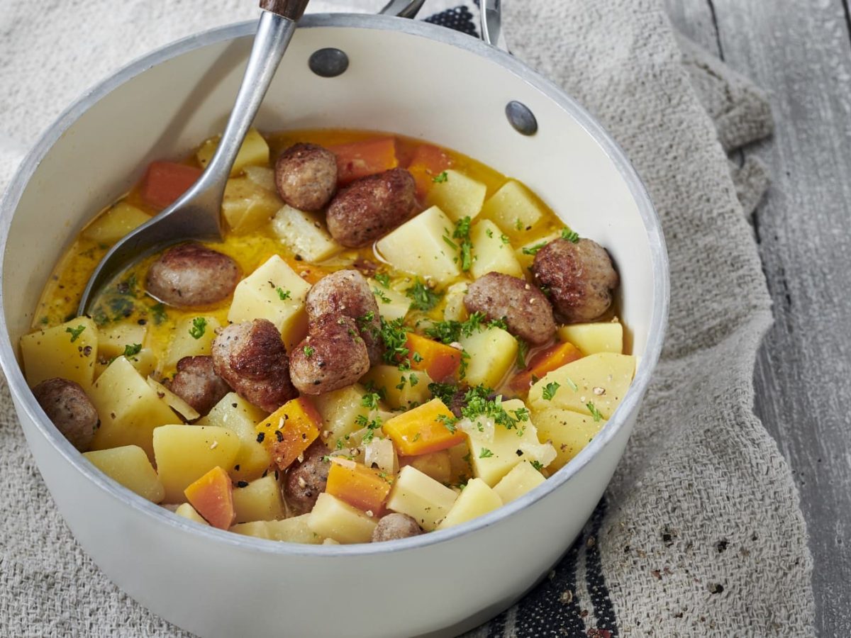 Pastinaken-Kartoffeltopf mit Hackbällchen, serviert in einer großen Schale und garniert mit frischer Petersilie.