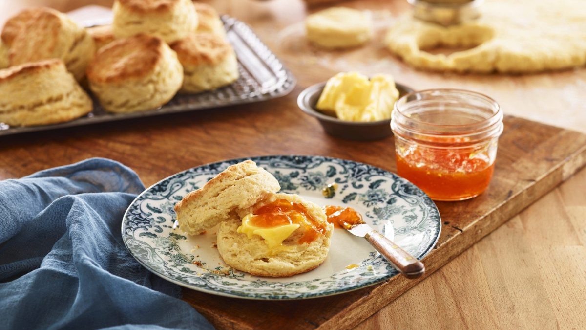 Ein blau-weißer Teller mit den Buttermilch-Biscuits auf einem Holzschneidebrett.