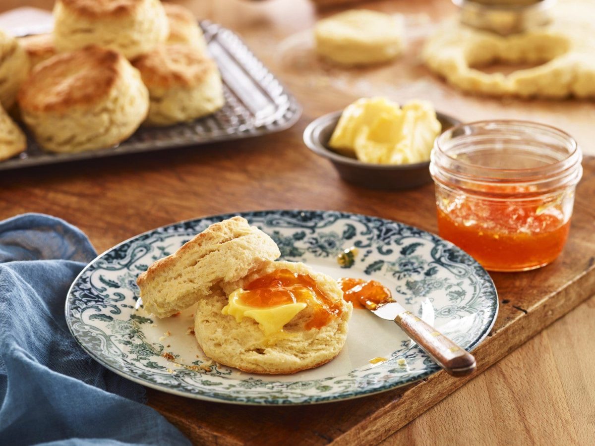 Ein blau-weißer Teller mit den Buttermilch-Biscuits auf einem Holzschneidebrett.