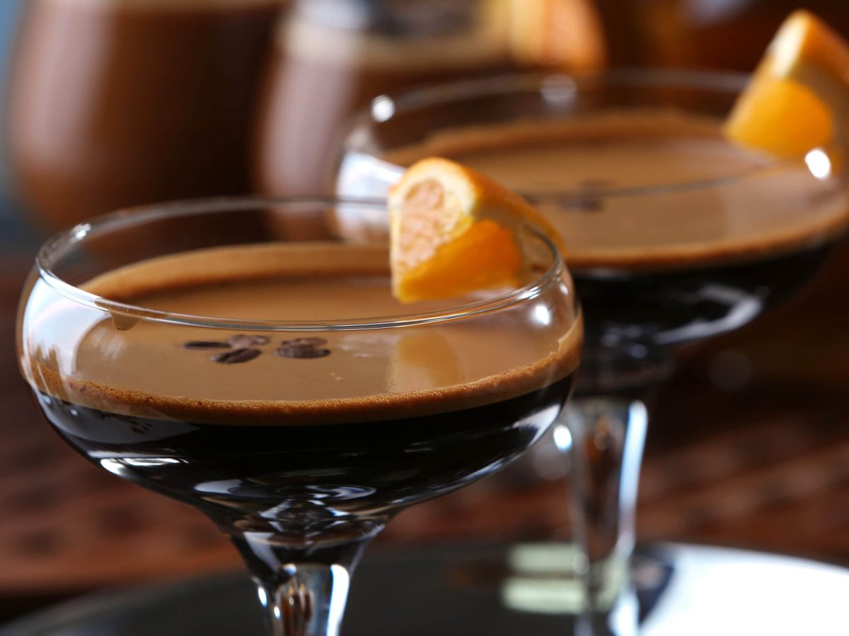 Zwei Chocolate Orange Espresso Martini in Martinigläsern mit Garnitur auf dunklem Untergrund. Frontalansicht.