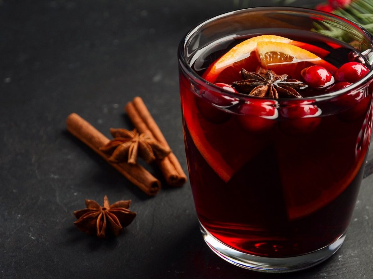 Ein Teeglas Cranberry Hot Toddy mit Orangenscheiben, Anis unc Cranberrys.