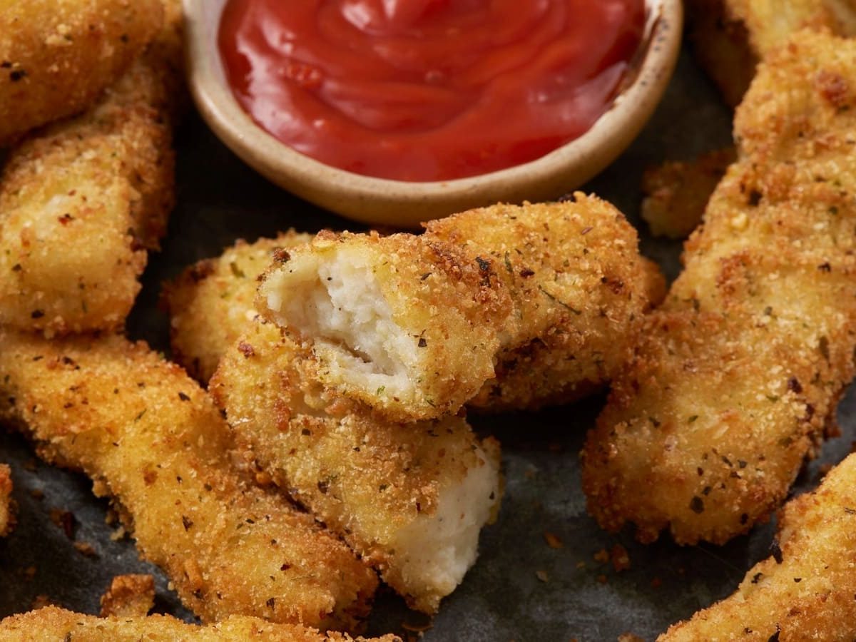 Mashed Potato Fries auf einem Holzbrett neben Ketchup.