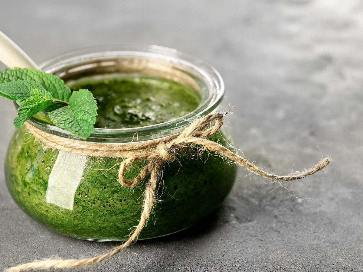 Ein Glas mit Minz-Pesto auf einem grauen Tisch.