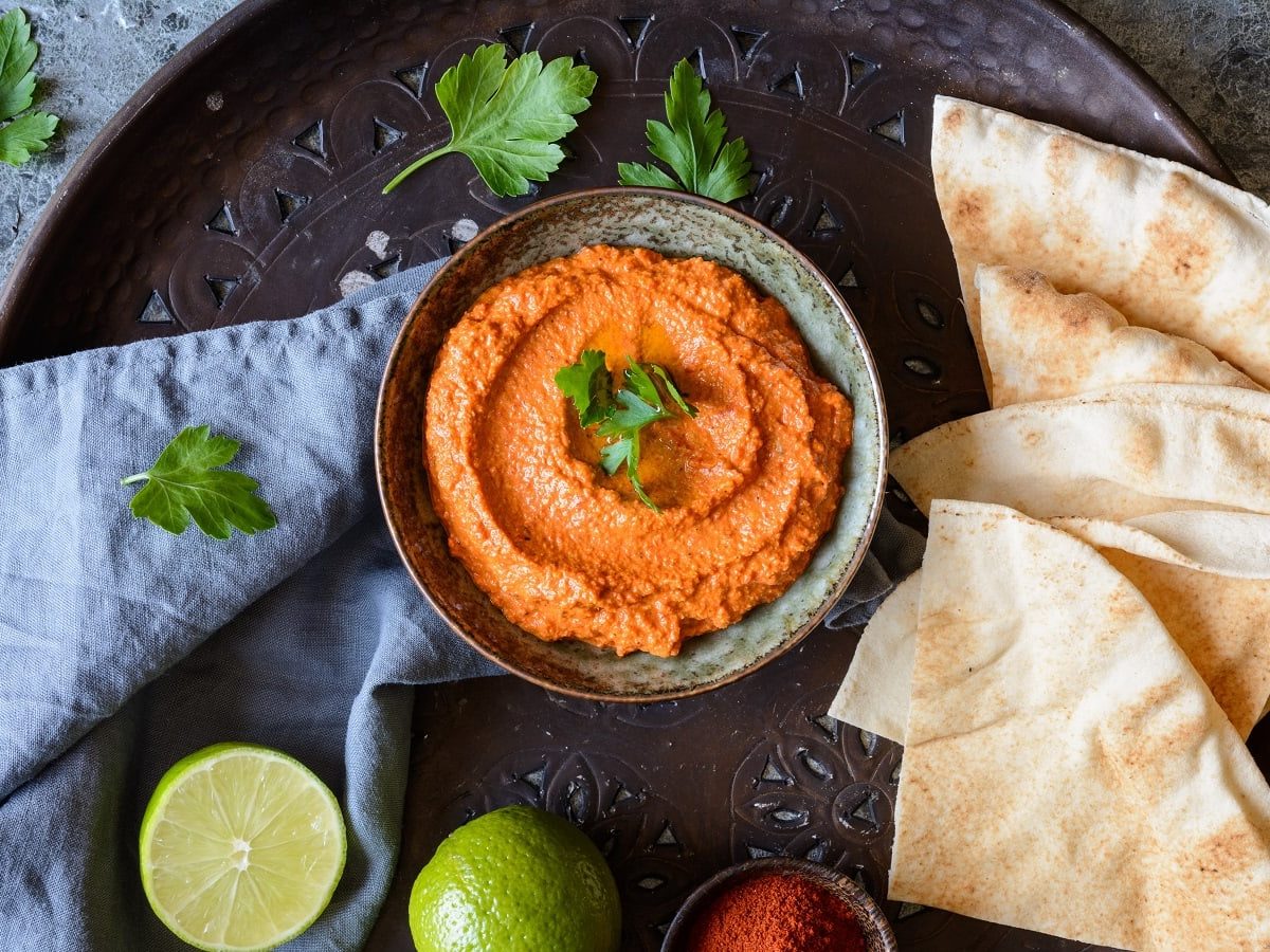 Eine kleine Schale mit Muhammara auf einem schwarzen Teller.