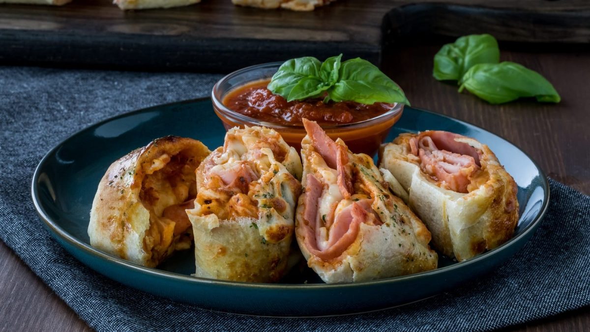 Ein schwarzer Teller mit Stromboli Pizza auf dunklem Hintergrund.