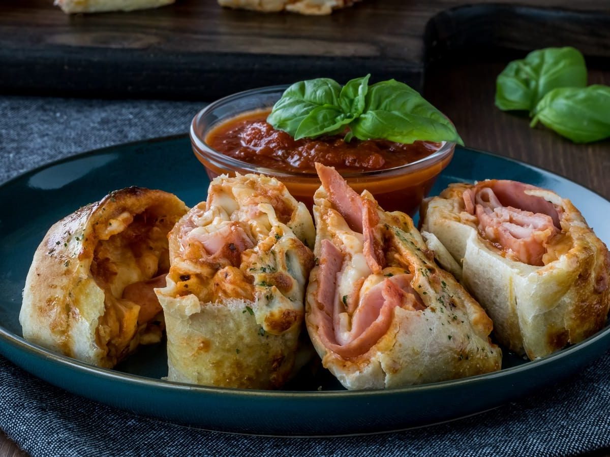 Ein schwarzer Teller mit Stromboli Pizza auf dunklem Hintergrund.