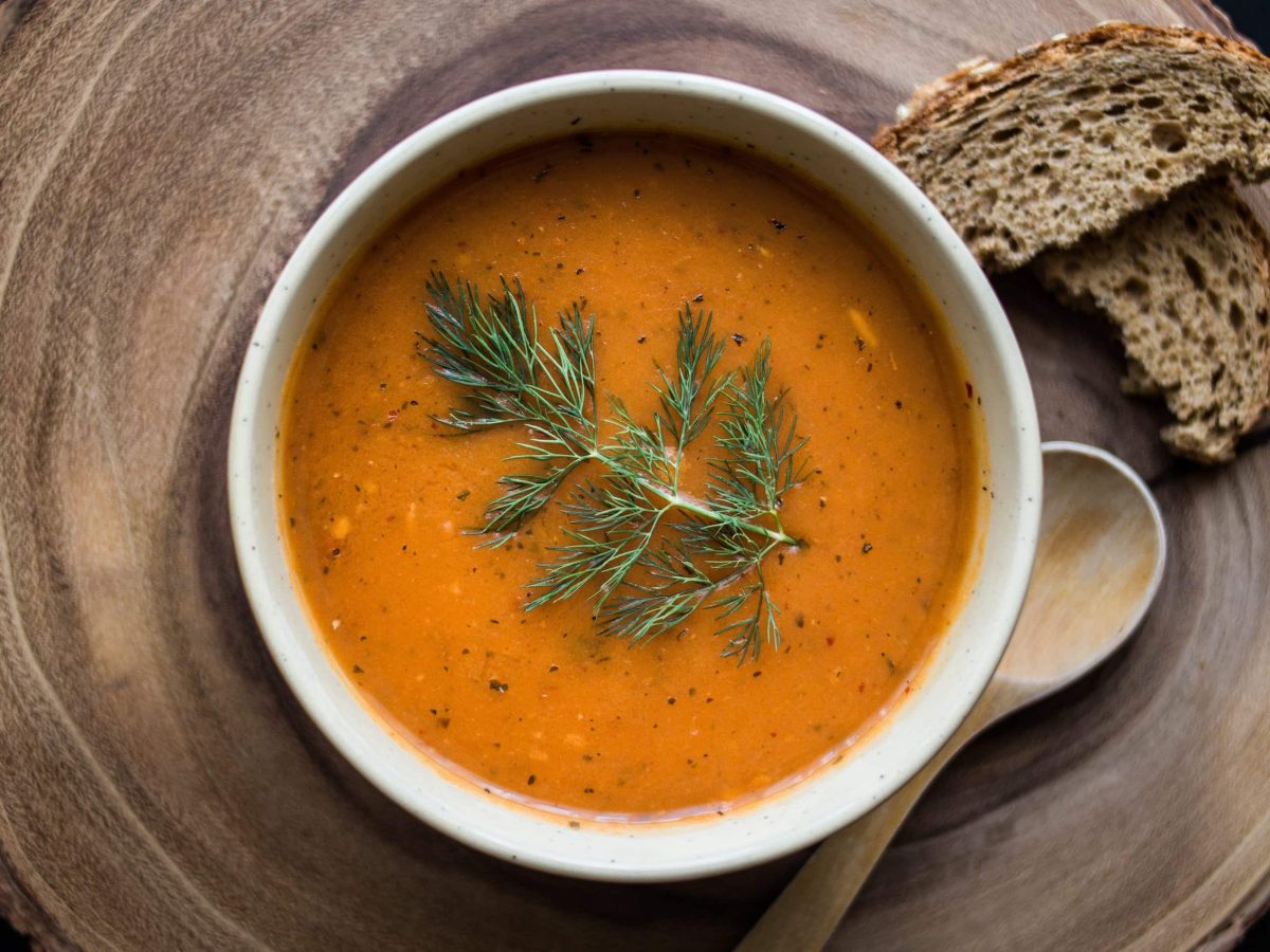 Eine Holzplatte mit Tarhana-Suppe und Brot.