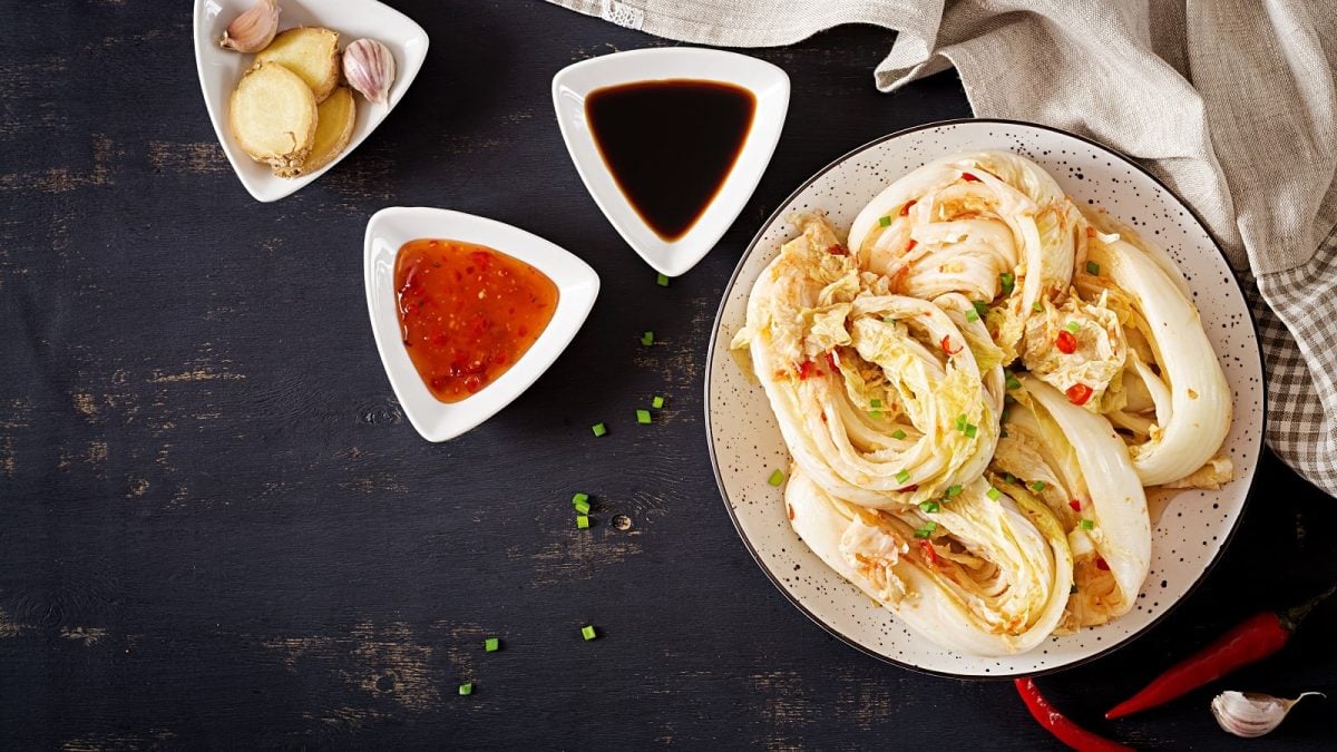 Ein Teller mit weißem Kimchi auf einem dunklen Tisch.