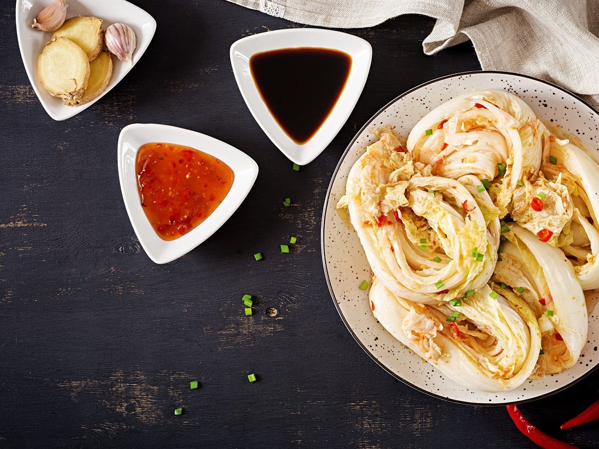 Ein Teller mit weißem Kimchi auf einem dunklen Tisch.