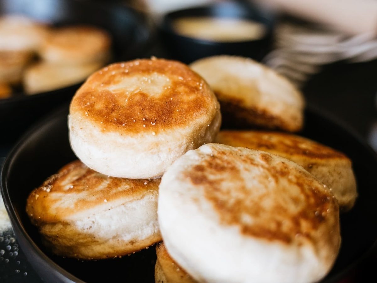 Mehrere English Muffins in einer schwarzen Pfanne mit unscharfem Hintergrund.