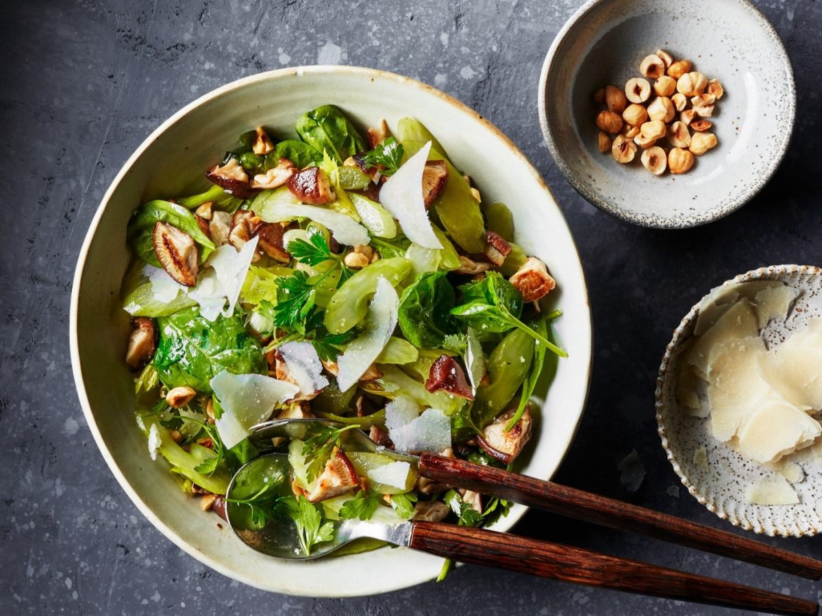 Eine weiße Schale mit dem grünen Salat und Haselnussdressing.